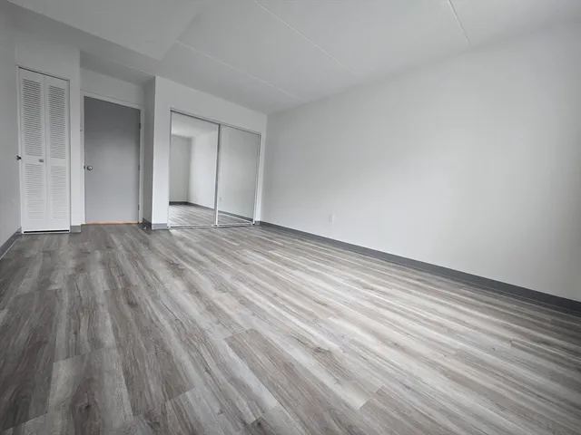 a view of an empty room with wooden floor and closet