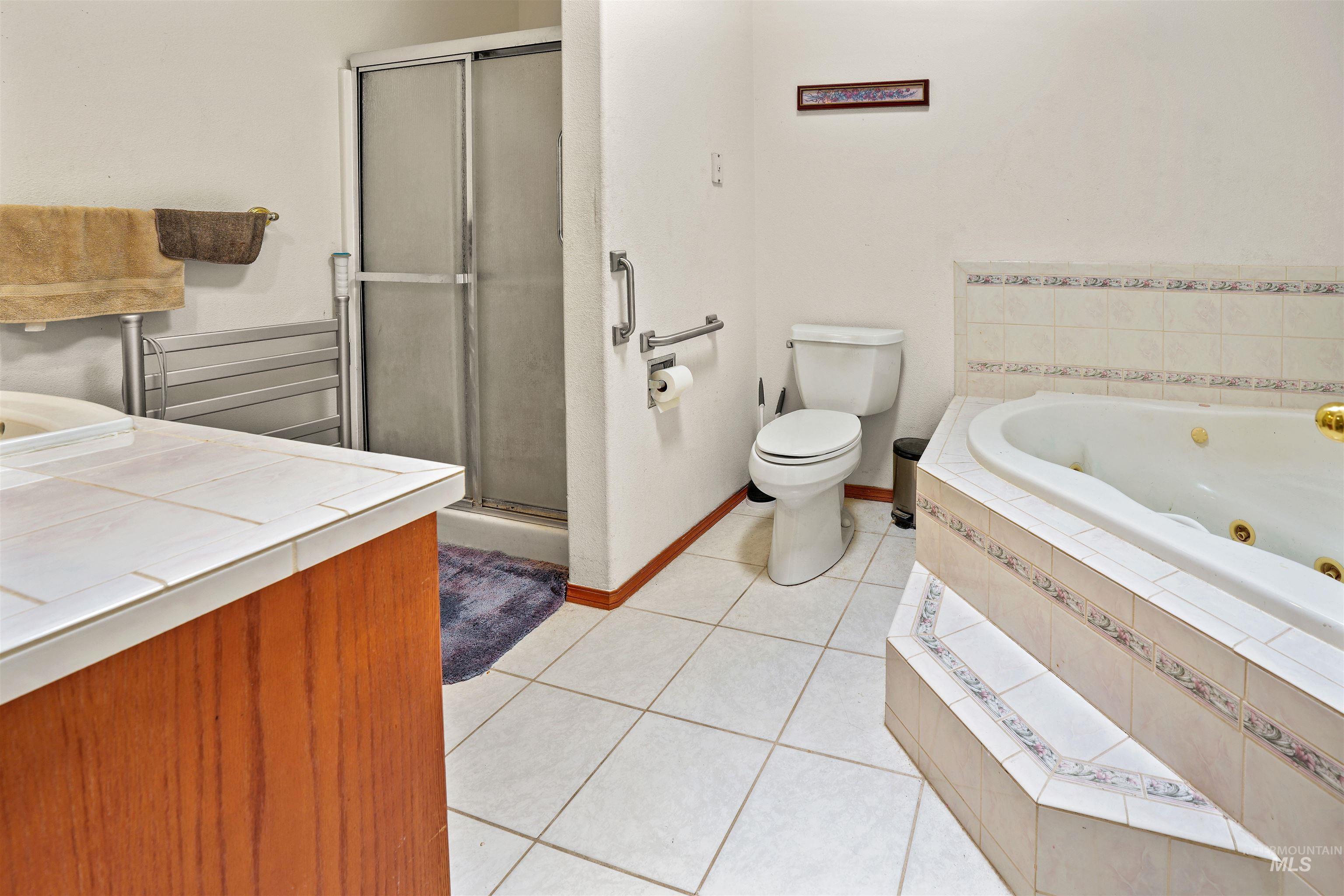 2750 South Perry Lane Clarkston, WA 99403 - Photo 30 of 47 Bathroom featuring a jetted tub, tiled shower with sliding glass door, white tile flooring, and a vanity with a tiled countertop