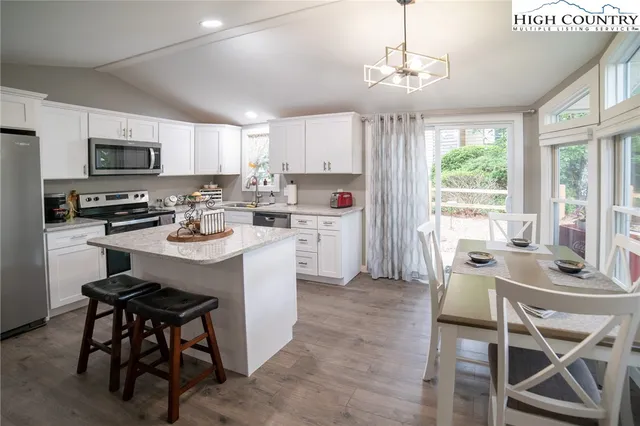 a kitchen with a stove a sink a microwave a dining table and chairs