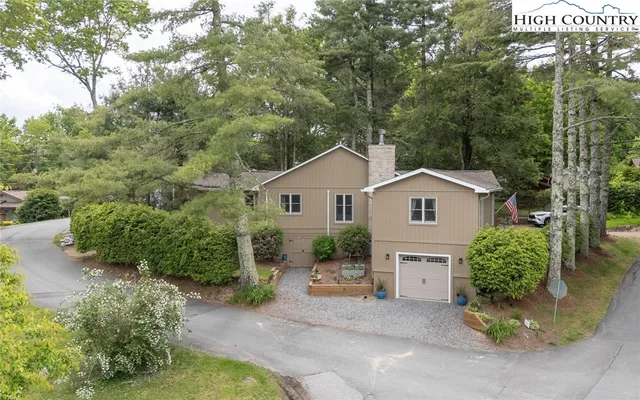 a view of a house with a yard and large tree