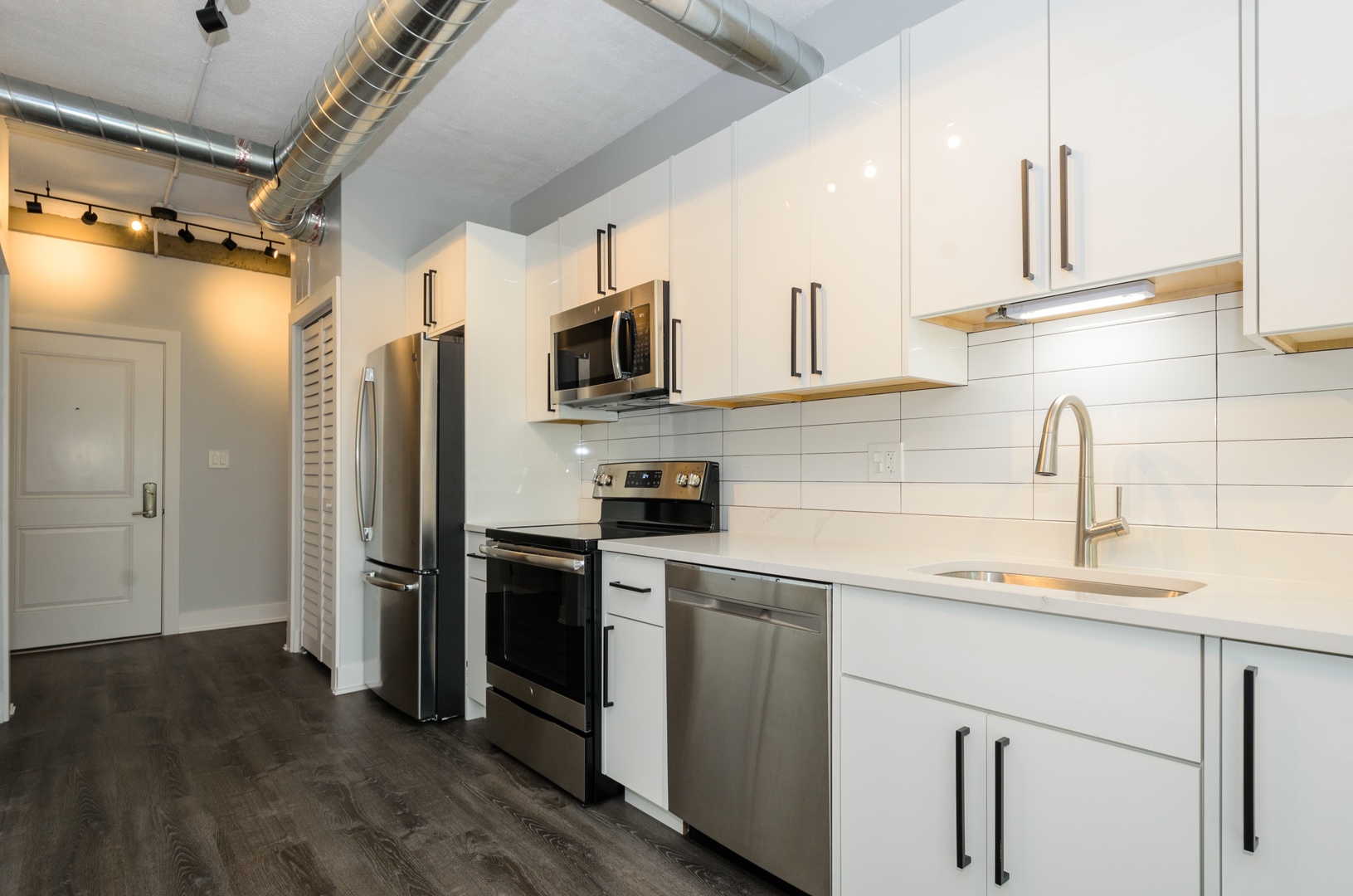 7645 North Sheridan Road, Unit 216 Chicago, IL 60626 - Photo 5 of 14 a kitchen with stainless steel appliances a sink cabinets and a wooden floor