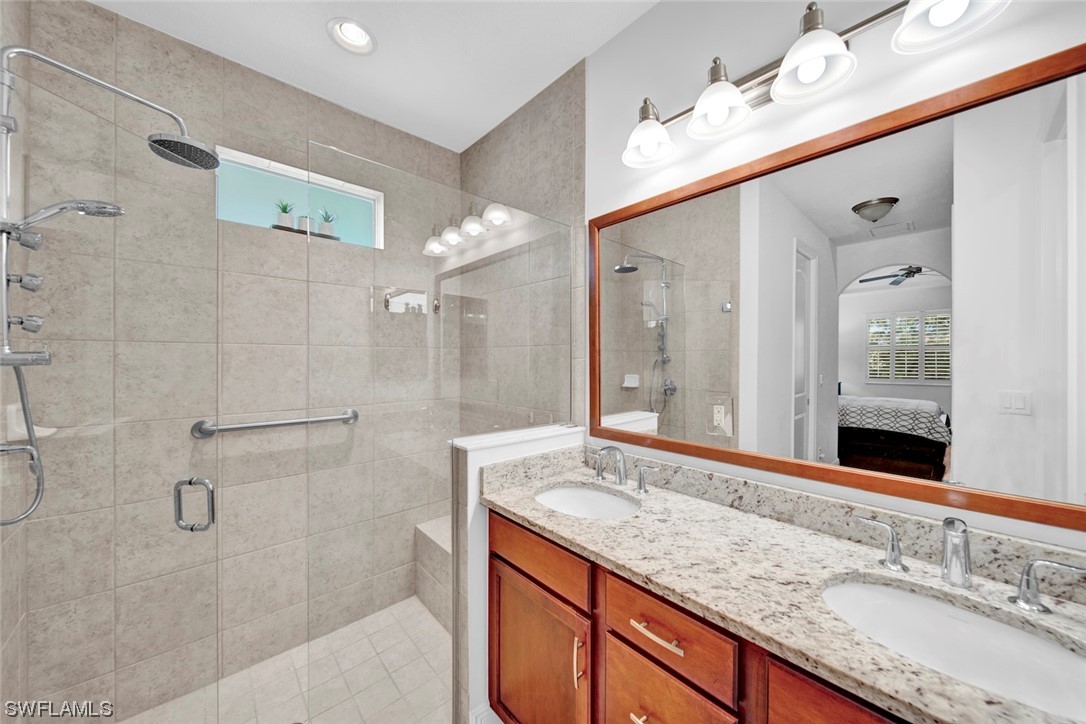 19630 Tesoro Way Estero, FL 33967 - Photo 18 of 44 a bathroom with a granite countertop double vanity sink mirror and shower