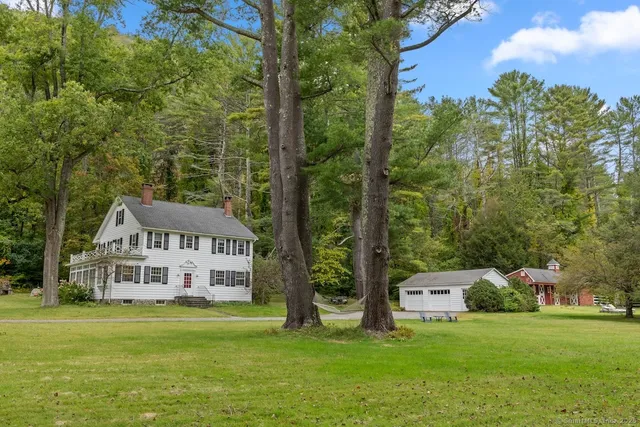 a view of a house with a big yard and large trees