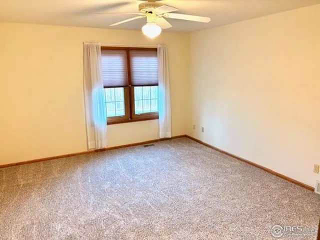 an empty room with a chandelier fan and windows