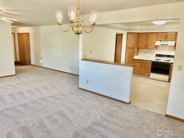 en empty room with a fireplace and chandelier