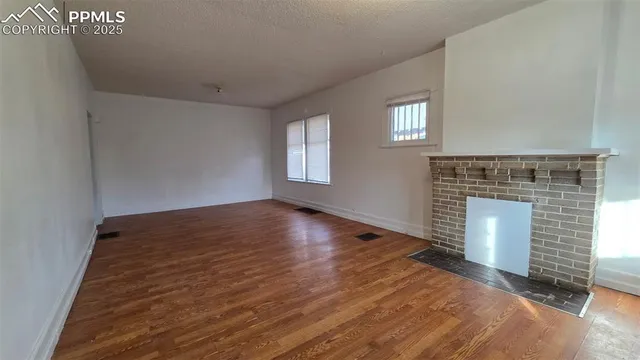 a view of empty room with wooden floor and fireplace