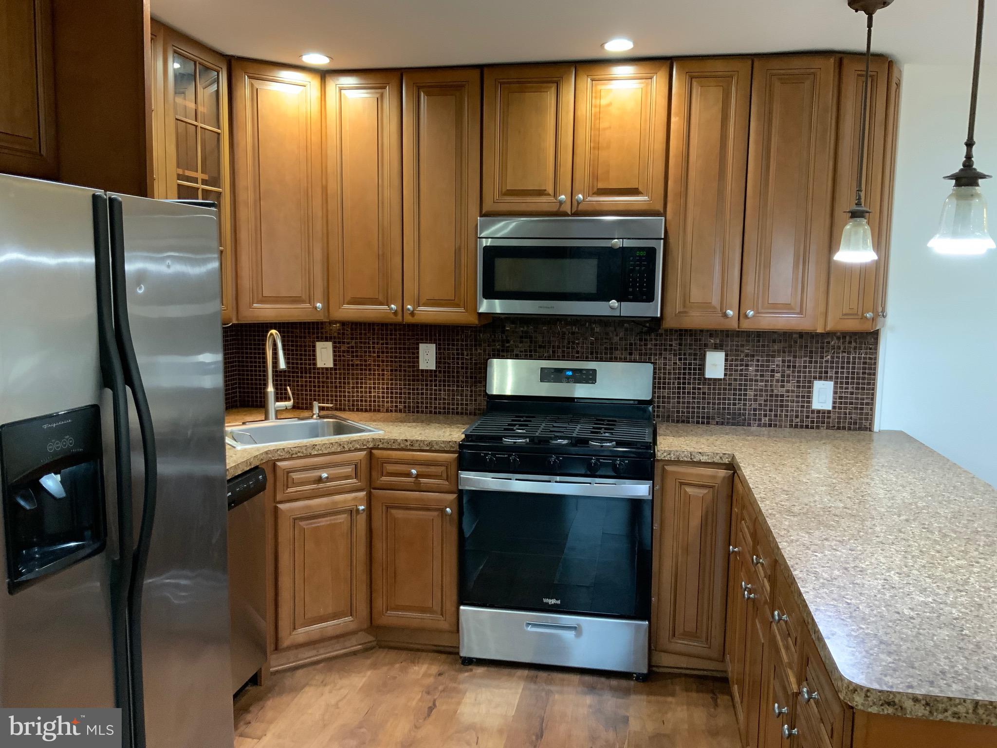 3744 Bel Pre Road, Unit 10 Silver Spring, MD 20906 - Photo 6 of 23 a kitchen with kitchen island granite countertop wooden cabinets and a stove