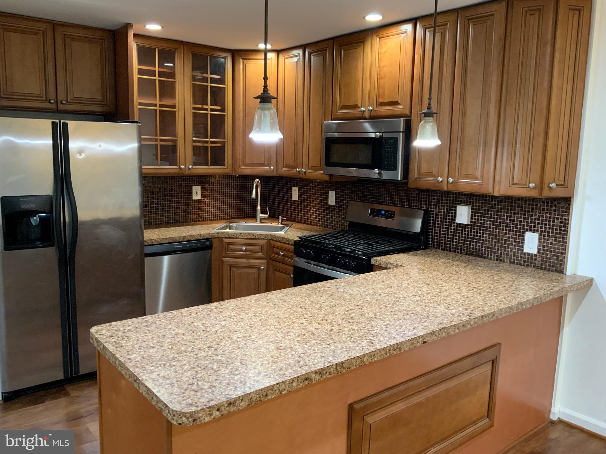 3744 Bel Pre Road, Unit 10 Silver Spring, MD 20906 - Photo 7 of 23 a kitchen with granite countertop a sink stainless steel appliances and cabinets