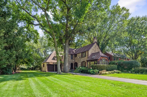 a front view of a house with a yard and large trees