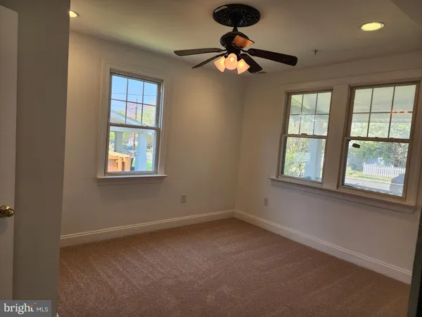 an empty room with windows and fan