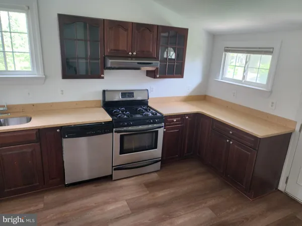a kitchen with stainless steel appliances granite countertop a sink a stove a microwave cabinets and a window