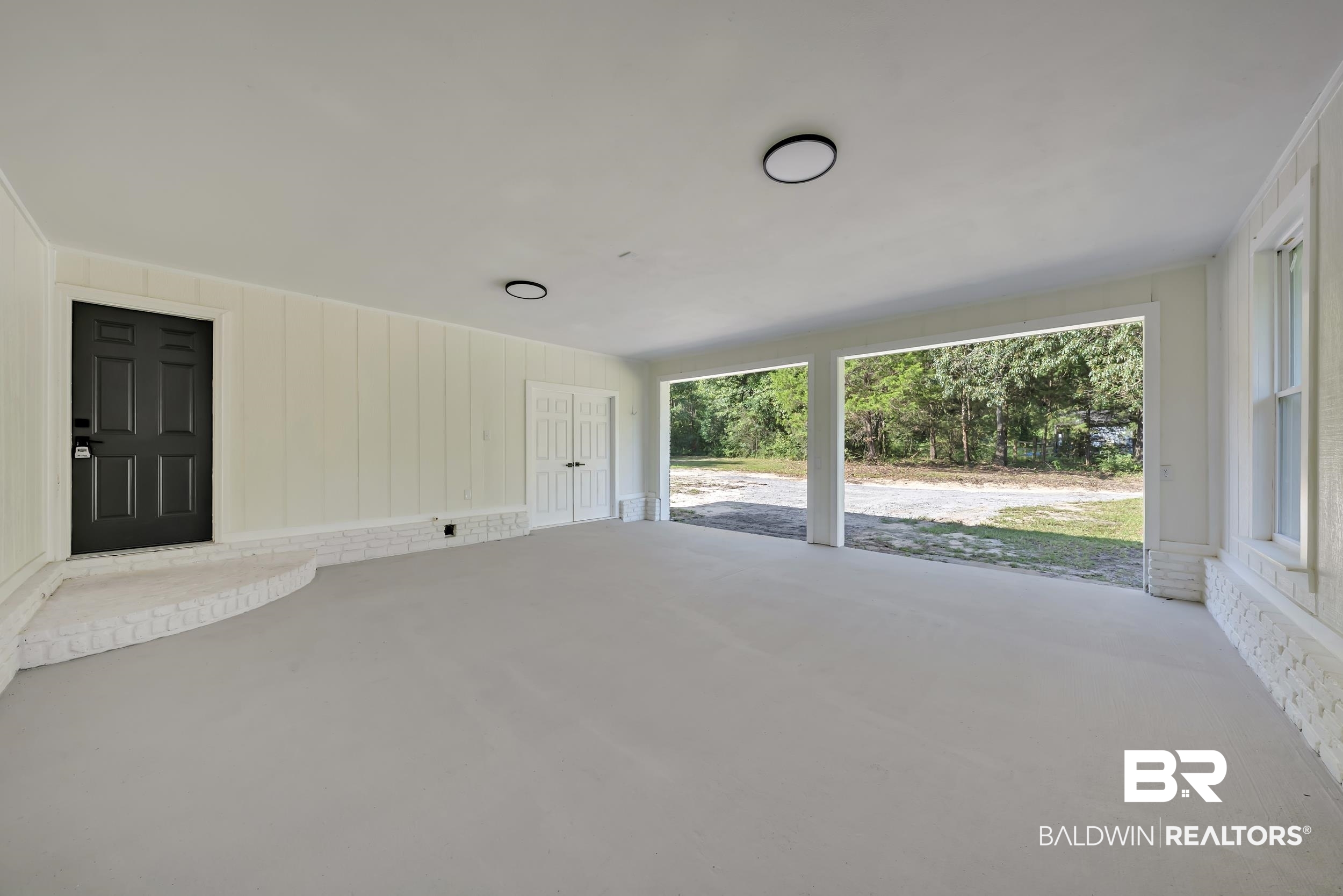 8170 Wilmer Georgetown Road Wilmer, AL 36587 - Photo 3 of 31 Spacious covered patio area featuring a light-colored concrete floor, white vertical paneling, and a white painted brick foundation