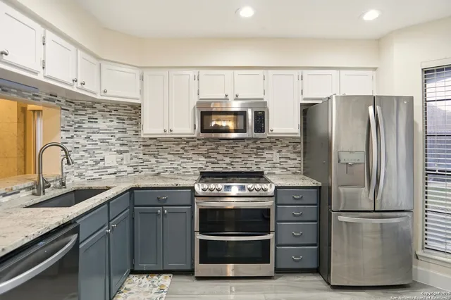 a kitchen with stainless steel appliances granite countertop a refrigerator sink and stove
