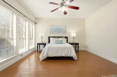 a spacious bedroom with a large bed and a chandelier fan