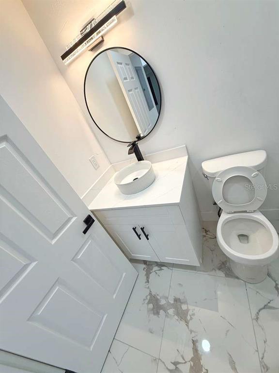 1048 Newbern Street Northeast Palm Bay, FL 32905 - Photo 26 of 29 a bathroom with a toilet a sink and mirror