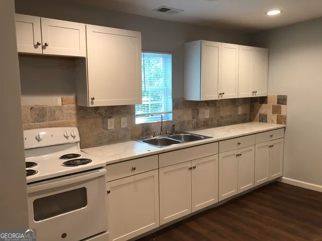 a kitchen with granite countertop white cabinets and white appliances