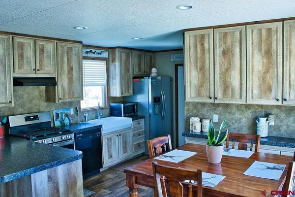 a kitchen with stainless steel appliances granite countertop sink stove refrigerator and cabinets