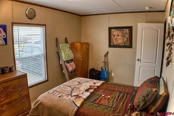 a bedroom with a bed and a flat tv screen on dresser