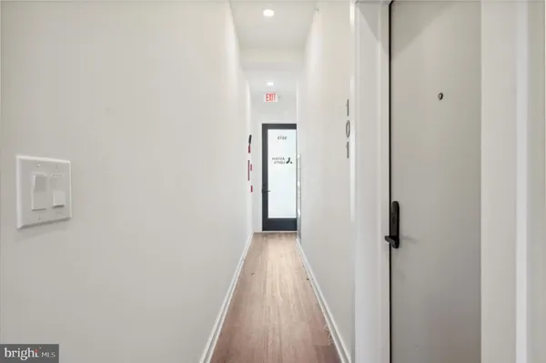 a view of a hallway with wooden floor and a bathroom