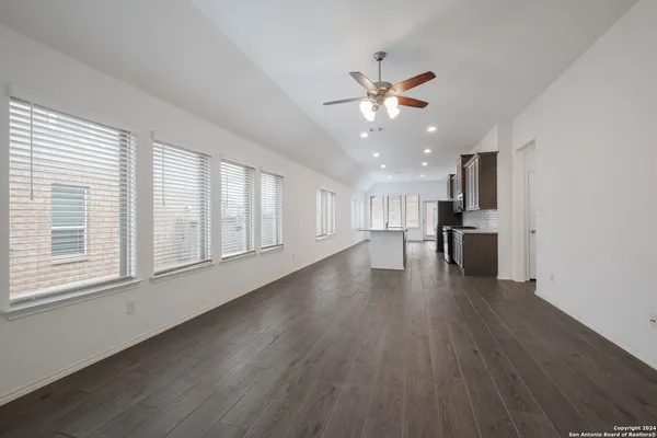 a view of an empty room with a kitchen and wooden floor
