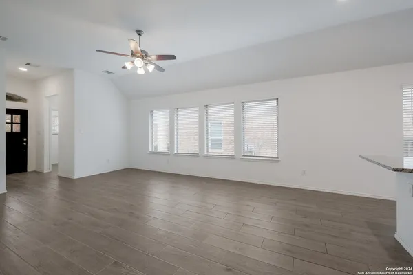a view of an empty room with wooden floor and a window