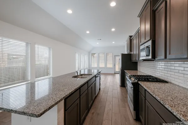a kitchen with granite countertop sink stove and refrigerator