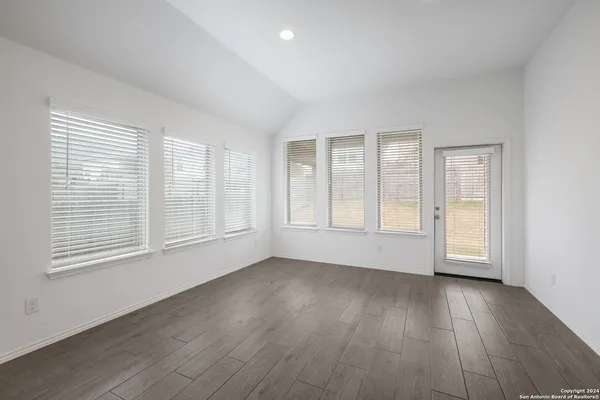 an empty room with wooden floor and windows