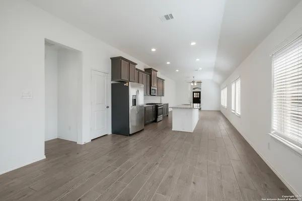 a view of a kitchen with a refrigerator a stove top oven and wooden floor