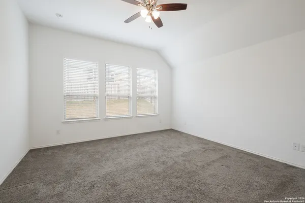 an empty room with chandelier fan and windows