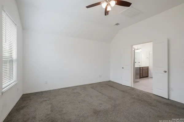 an empty room with chandelier fan and windows