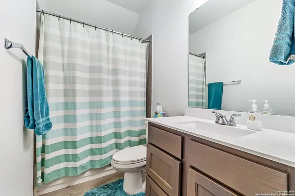 a bathroom with a sink a toilet a shower curtain and a mirror