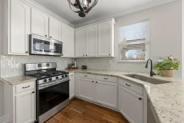 a kitchen with granite countertop a stove a sink and a microwave