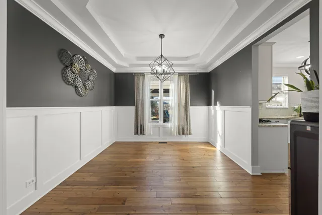 a view of a hallway with wooden floor and a kitchen