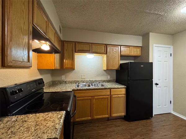 a kitchen with a stove a refrigerator and a wooden cabinets