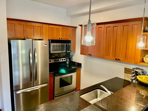 a kitchen with stainless steel appliances granite countertop a refrigerator and a stove top oven