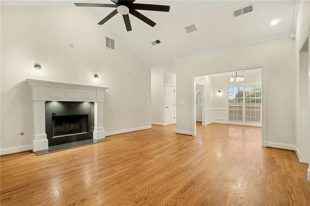 a view of an empty room with wooden floor fireplace and a window