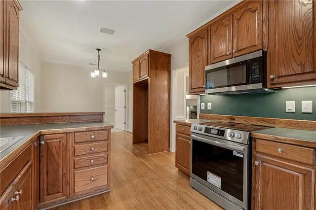a kitchen with granite countertop wooden cabinets stainless steel appliances and wooden floor