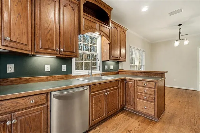 a kitchen with stainless steel appliances granite countertop a sink and dishwasher with wooden cabinets