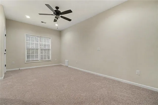 an empty room with windows and ceiling fan