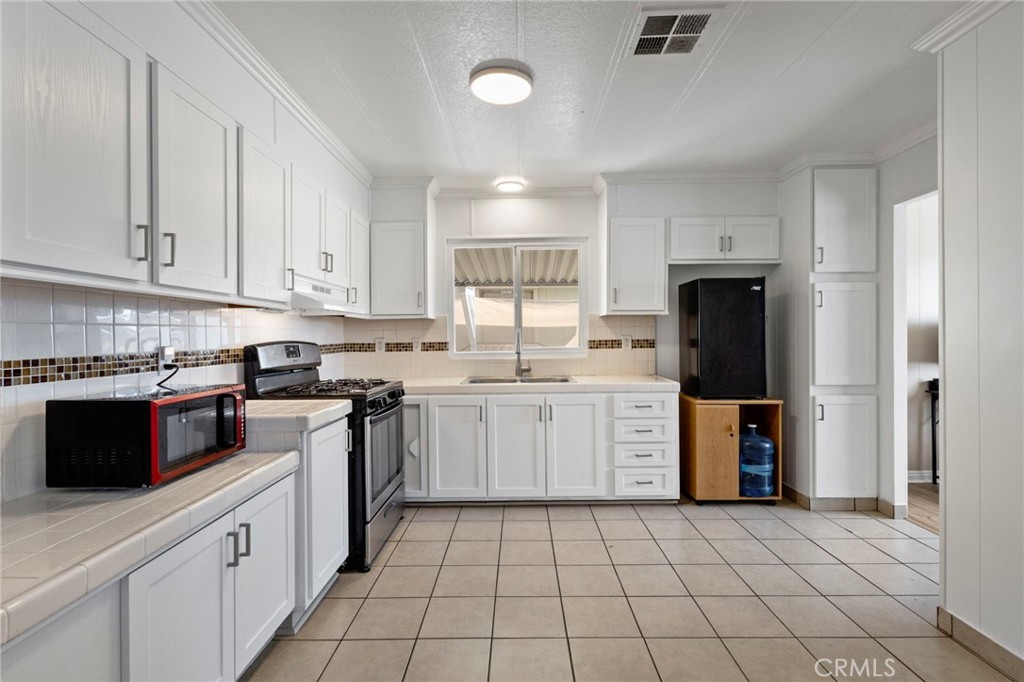 22838 Bear Valley Road, Unit 64 Apple Valley, CA 92308 - Photo 8 of 22 a kitchen with a sink a stove top oven and cabinets
