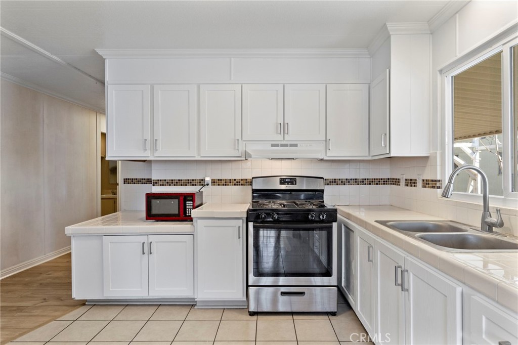 22838 Bear Valley Road, Unit 64 Apple Valley, CA 92308 - Photo 9 of 22 a kitchen with white cabinets and appliances
