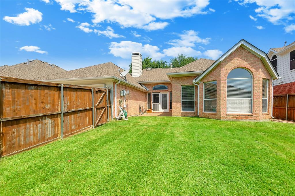 1404 Ranch Hill Drive Irving, TX 75063 - Photo 28 of 31 Expansive green lawn with a brick exterior, featuring a large arched window and a covered patio area