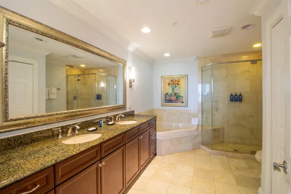 a bathroom with a granite countertop double vanity sink a mirror a shower and a bathtub