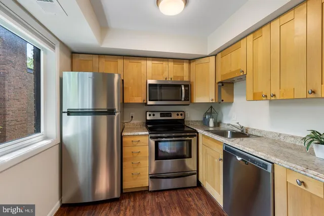 a kitchen with stainless steel appliances granite countertop a refrigerator a stove a sink and a microwave