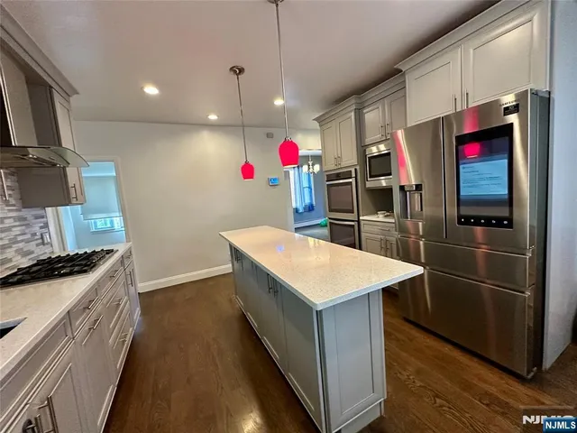 a kitchen with stainless steel appliances granite countertop a kitchen island a stove and a refrigerator