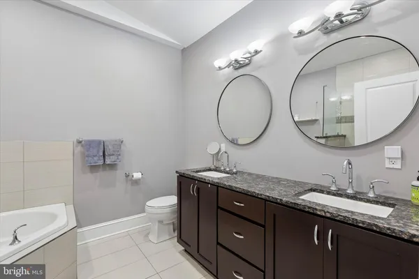 a bathroom with a granite countertop toilet a sink and a mirror