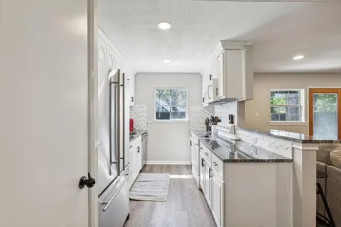 a kitchen with granite countertop a sink stove and refrigerator