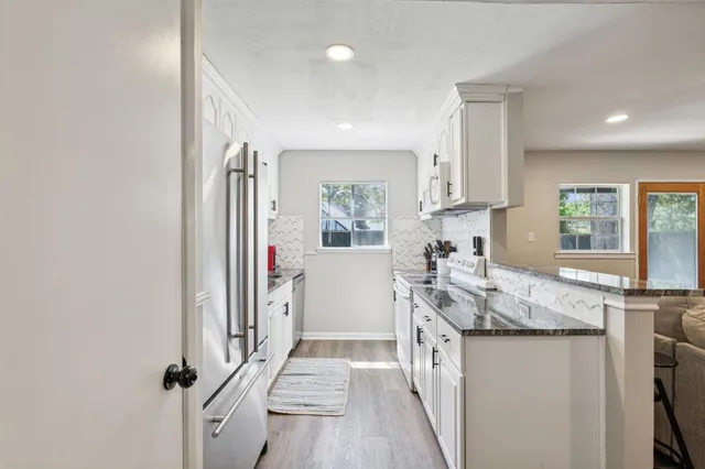 a kitchen with granite countertop a sink stove and refrigerator