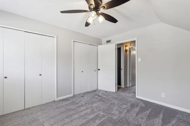 a view of an empty room and chandelier fan