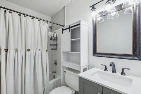 a bathroom with a shower sink vanity and mirror